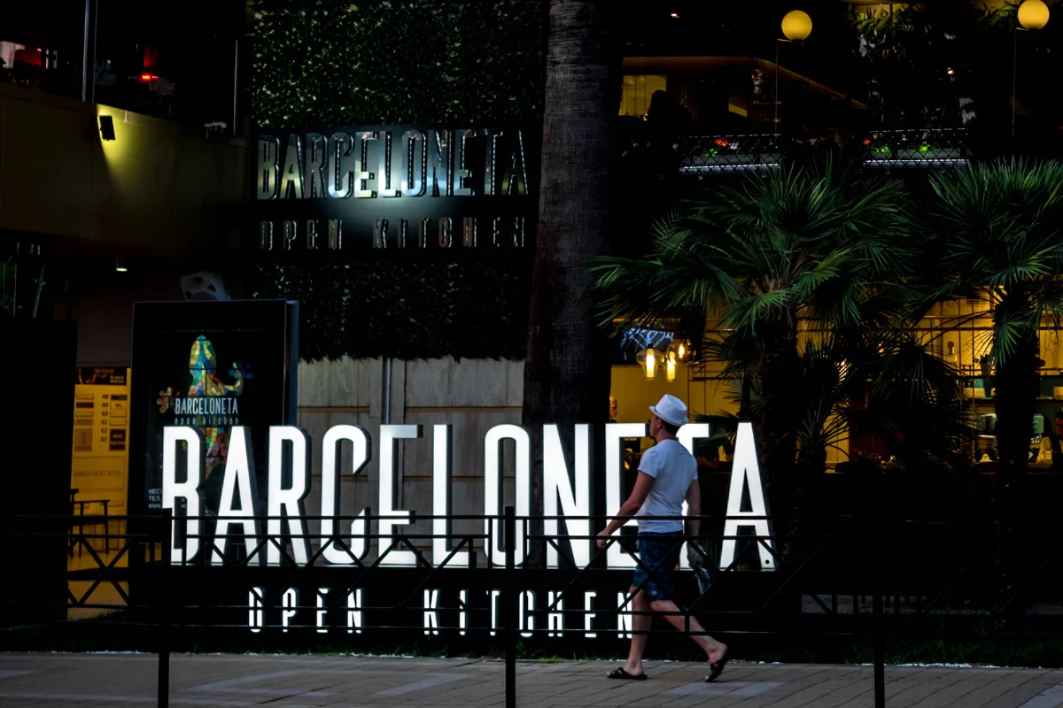 Carrer estret de la Barceloneta amb taules de bar a la vorera i roba estesa als balcons