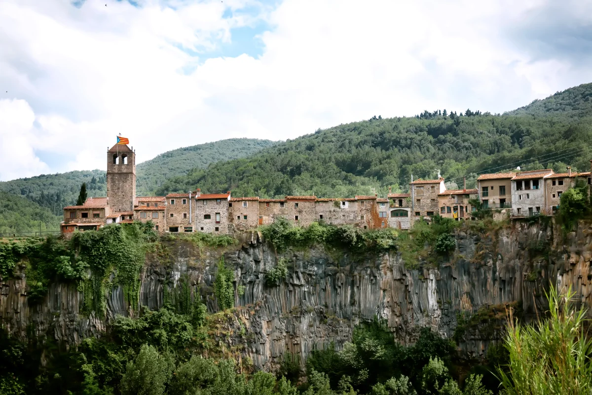 Castellfollit de la Roca visto desde la distancia, con el pueblo sobre el acantilado basáltico de la Garrotxa y los ríos Fluvià y Toronell al pie del precipicio