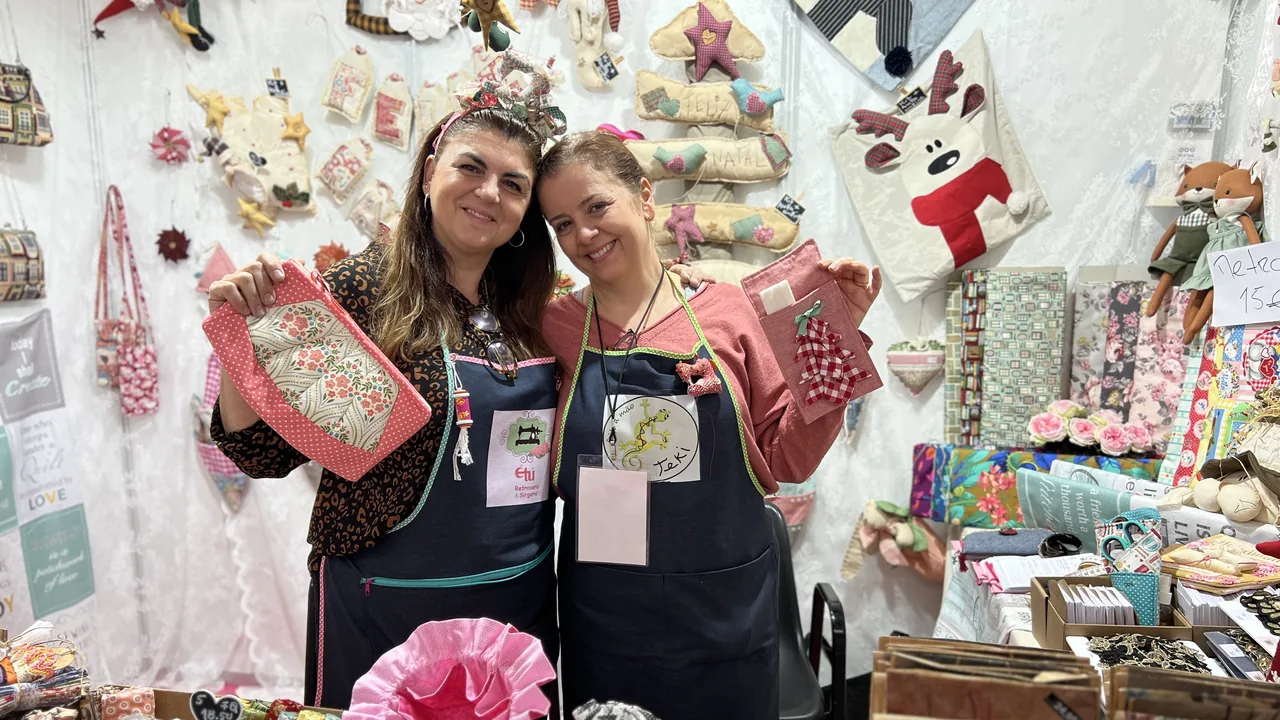 Dos artesanas sonrientes en su stand de Creativa Barcelona, rodeadas de piezas textiles y decoración hecha a mano