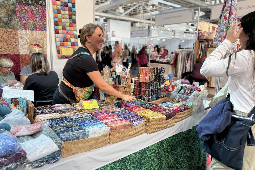 Stand de telas de patchwork en cestas con visitantes comprando en Creativa Barcelona