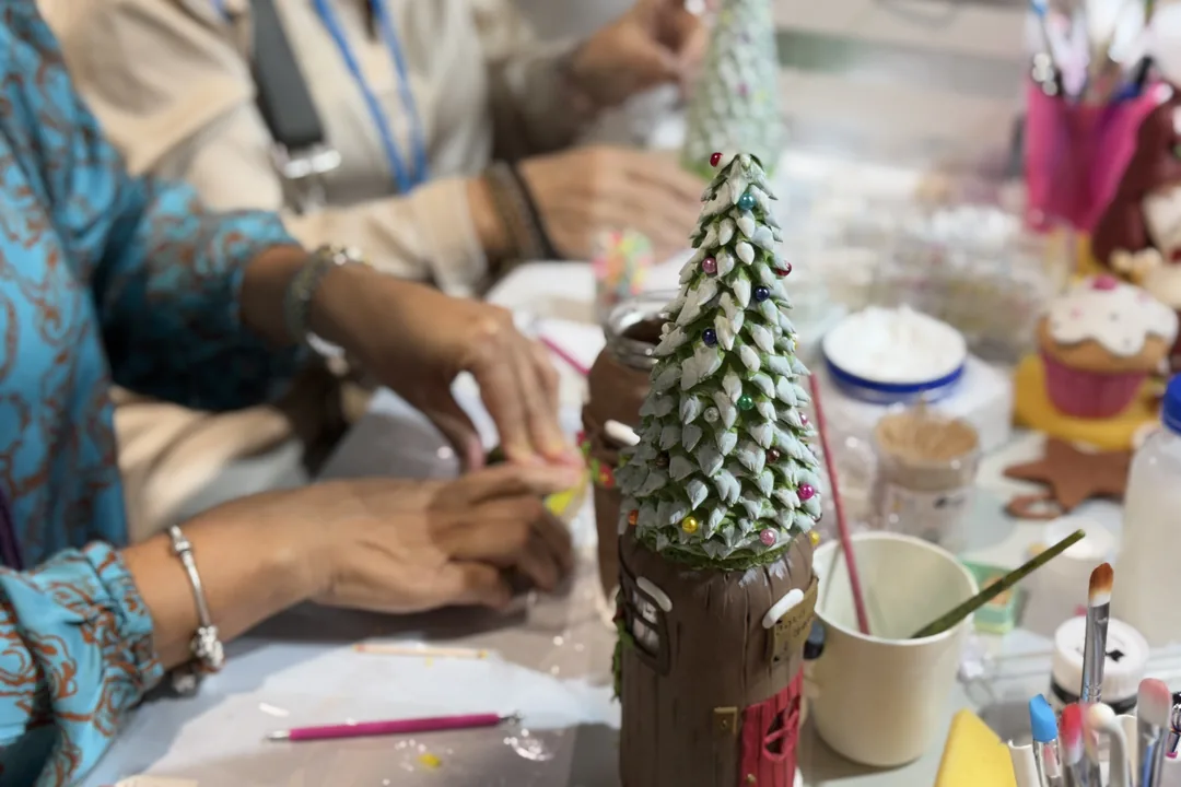 Participante decorando un árbol de Navidad de cerámica con pincel en un taller de Creativa Barcelona