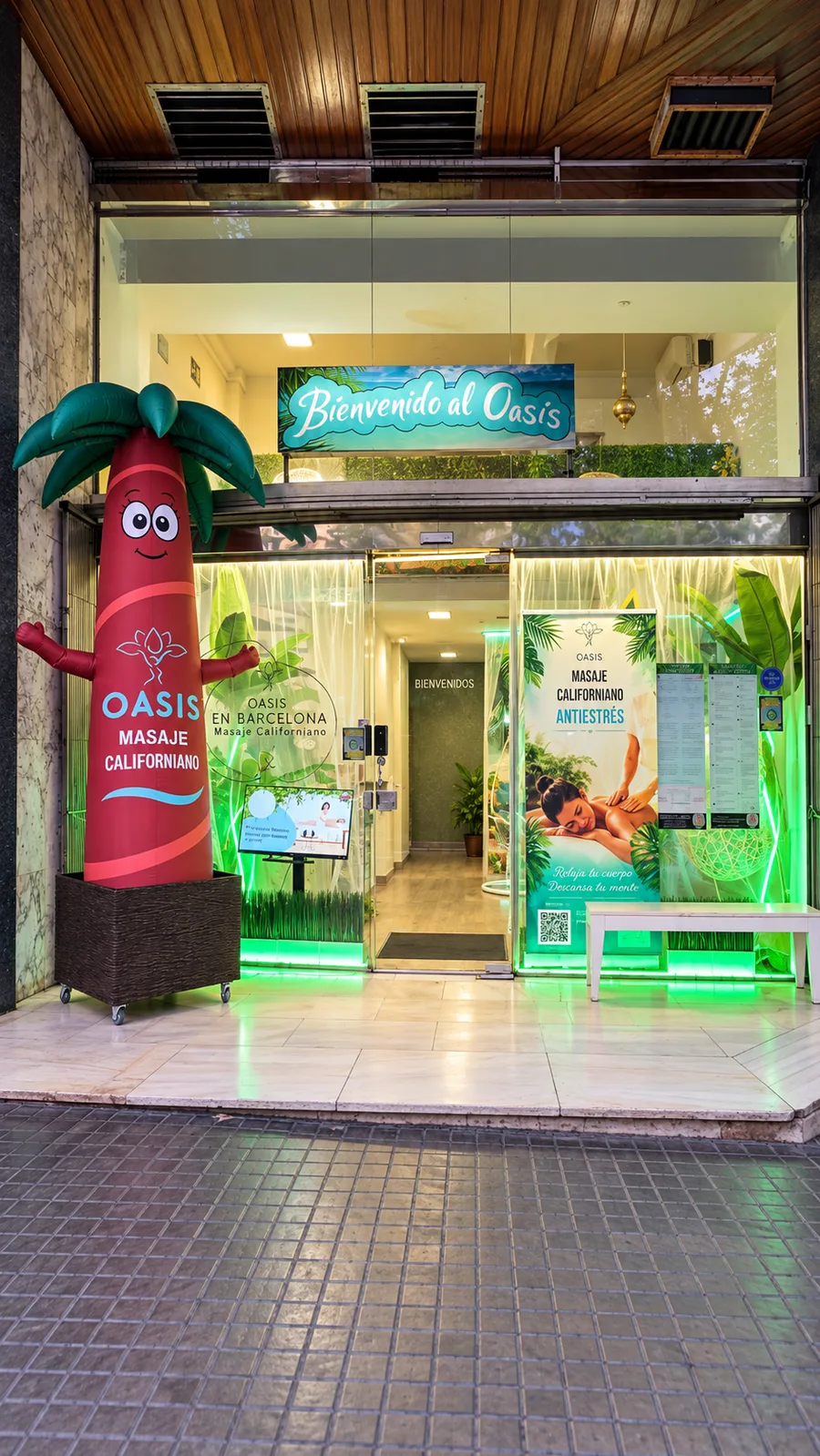 Fachada de OASIS EN BARCELONA en Passeig de Sant Joan con Diri, la palmera hinchable que hace de mascota, junto a la entrada